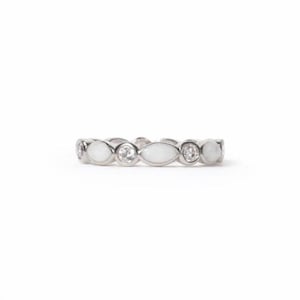 May include: A silver ring with a repeating pattern of white oval and round stones, alternating with clear, round gemstones. The ring is set against a white background, highlighting its delicate design and sparkle.