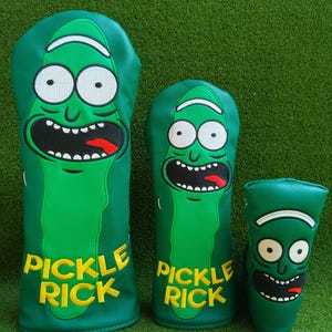 May include: Three green golf club head covers featuring a cartoon pickle character with white eyes, a black mouth, and a red tongue. The words "PICKLE RICK" are in yellow block letters. The covers are on a green background.