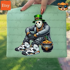 May include: A green, rectangular item featuring a graphic of a figure in a hockey mask and a green leprechaun hat, seated with a pot of gold. The figure wears a gold chain, watch, and black and white sneakers. The background has a barbed wire design.