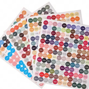 May include: Sheets of colorful round stickers with numbers printed on them. The stickers are arranged in a variety of colors, including pink, blue, orange, green, and purple. The stickers are used for organization and labeling.