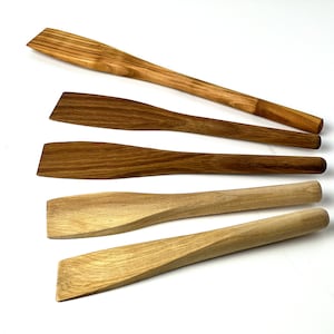 Könnte beinhalten: Vier Holzlöffel in verschiedenen Größen und Formen. Die Löffel sind aus hellem braunem Holz mit natürlicher Oberfläche.