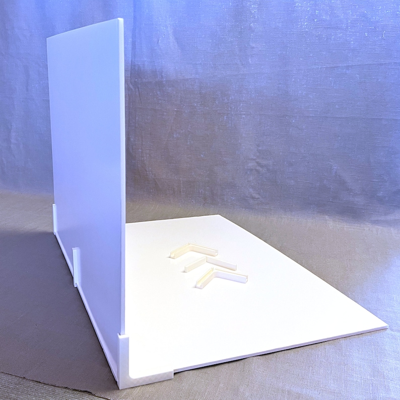 May include: White backdrop for product photography with a white background and a white back panel. The backdrop is made of foam board and has four white plastic corner brackets.
