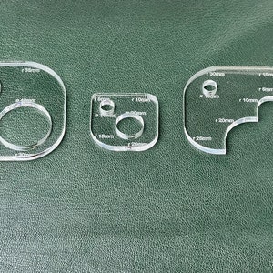 Op de afbeelding: Drie transparante kunststof sjablonen voor knutselen, met verschillende cirkel- en kromme vormen die in millimeters zijn gemarkeerd. De grootste sjabloon heeft een cirkel van 40 mm, een cirkel van 30 mm en een cirkel van 16 mm. De middelste sjabloon heeft een cirkel van 20 mm, een cirkel van 16 mm en een cirkel van 10 mm. De kleinste sjabloon heeft een kromme van 26 mm, een kromme van 20 mm, een kromme van 10 mm en een kromme van 5 mm.