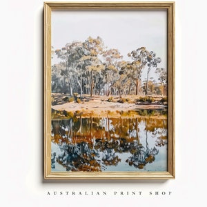 May include: A framed watercolor painting of a forest reflecting in a still body of water. The trees are a mix of green, brown, and yellow, and the water is a deep blue with hints of orange and yellow.