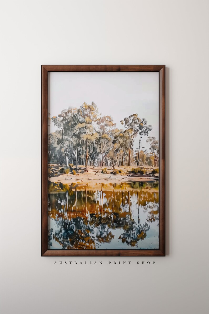 May include: A framed print of a landscape painting featuring a reflection of trees in a still body of water. The trees are a mix of green and brown, and the water is a deep blue. The frame is a dark wood.