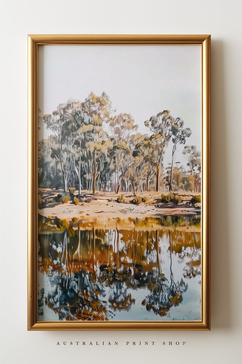 May include: A framed painting of a landscape with trees reflected in a still body of water. The trees are a mix of green and brown, and the water is a deep blue with hints of gold. The frame is gold.