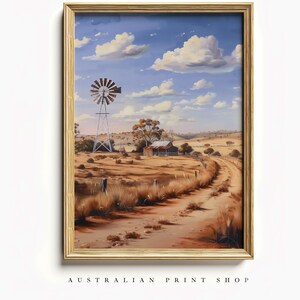 May include: A framed painting of a rural Australian landscape with a windmill, a small wooden shack, and a dirt road leading into the distance. The sky is blue with white clouds.