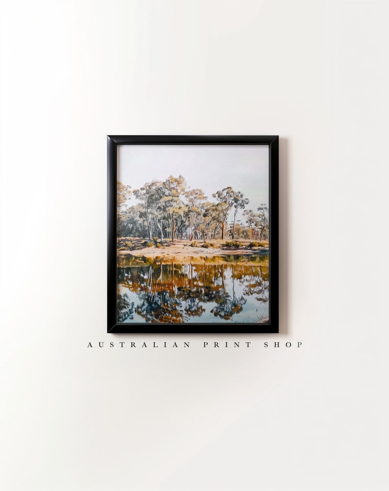 May include: A framed print of a landscape scene with a lake reflecting trees in the water. The trees are a mix of green and yellow, and the water is a deep blue. The print is in a black frame.