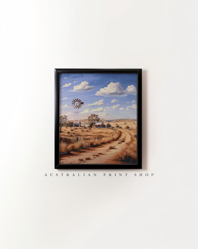 May include: A framed painting of a rural Australian landscape with a windmill, a farmhouse, and a dirt road leading into the distance. The sky is blue with white clouds.