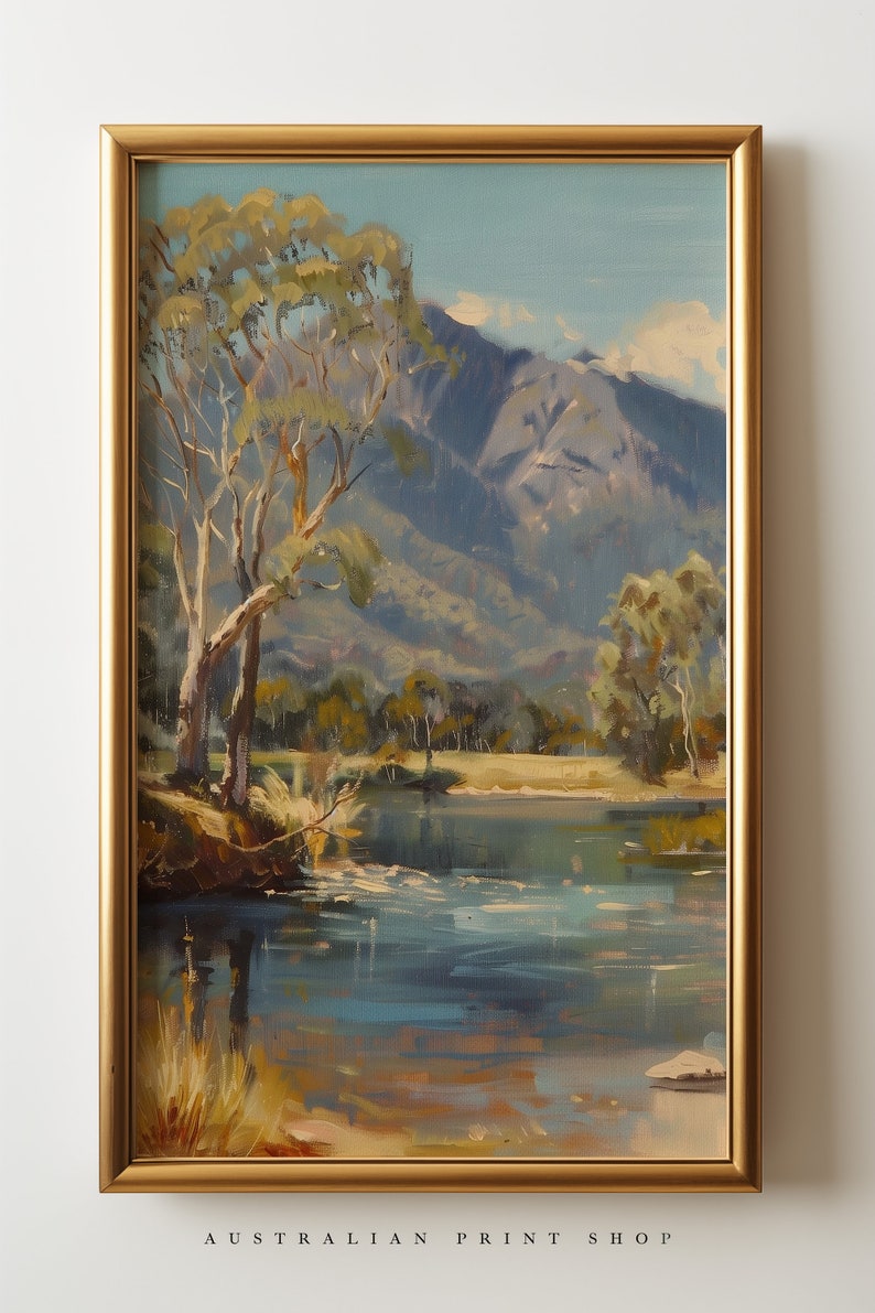 May include: A framed painting of a landscape scene with a lake, trees, and mountains in the background. The lake is a light blue color and the mountains are a dark blue color. The trees are a light green color and the sky is a light blue color.