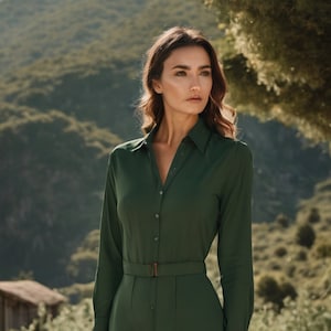 Puede incluir: Un vestido verde oscuro de botones de manga larga con cinturón. El vestido tiene cuello y una falda ligeramente acampanada.