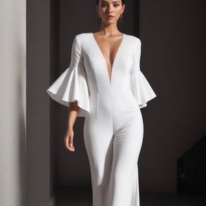 Puede incluir: Un mono blanco con un escote en V profundo y mangas anchas y fluidas. El mono tiene un corpiño ajustado y pantalones de pierna ancha.