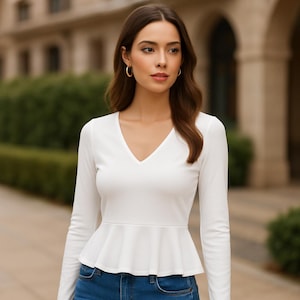 Pode incluir: Uma blusa branca de manga comprida com decote em V e uma bainha peplum com babados.