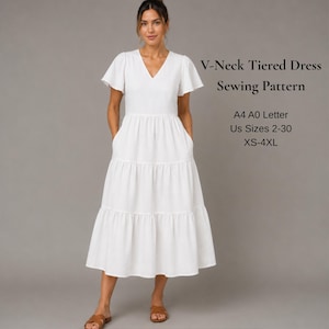 Op de afbeelding: Een witte gelaagde jurk met V-hals, korte wapperende mouwen en een rok tot halverwege de kuit. De tekst luidt: V-Neck Tiered Dress Sewing Pattern, A4 A0 Letter, US Sizes 2-30, XS-4XL. Het kledingstuk heeft een aansluitend lijfje en een wijde rok.