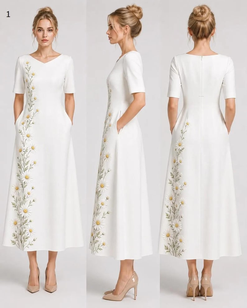 May include: A white midi dress featuring short sleeves, a V-neckline, and a vertical floral embroidery pattern of daisies with yellow centers and green stems running down the side. The dress includes side pockets and a concealed back zipper closure.