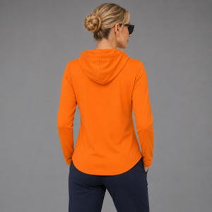 May include: A bright orange long-sleeve hooded pullover shirt with a hood and a curved hemline, paired with dark navy blue pants. The garment features a solid color design with long sleeves and a hood, providing a simple and functional appearance.