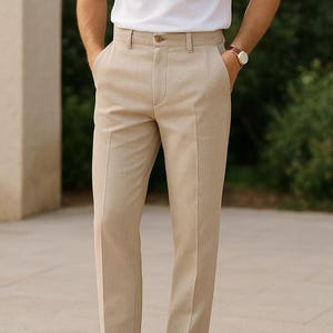 Può includere: Pantaloni beige slim fit con chiusura a bottone e zip. I pantaloni hanno una gamba dritta e una lunghezza leggermente cropped.