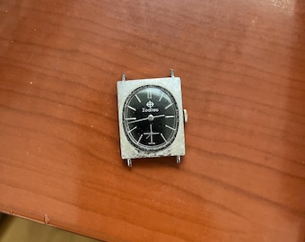 Reloj Zodiac vintage con esfera rectangular plateada y segundero ovalado negro.