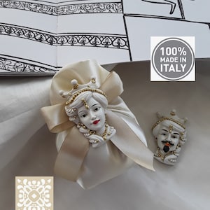 Può includere: Due figurine in ceramica di una donna e un uomo con corone dorate e dettagli decorativi. Le figurine sono su uno sfondo bianco con una borsa di raso beige e un'etichetta 100% Made in Italy.