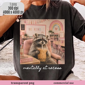 Peut inclure: Un t-shirt gris anthracite avec un motif représentant un raton laveur portant des lunettes, assis sur une chaise rose et tenant un thé aux perles. Le décor montre une salle de classe avec un arc-en-ciel et le texte BE KIND. Inscription mentally at recess.