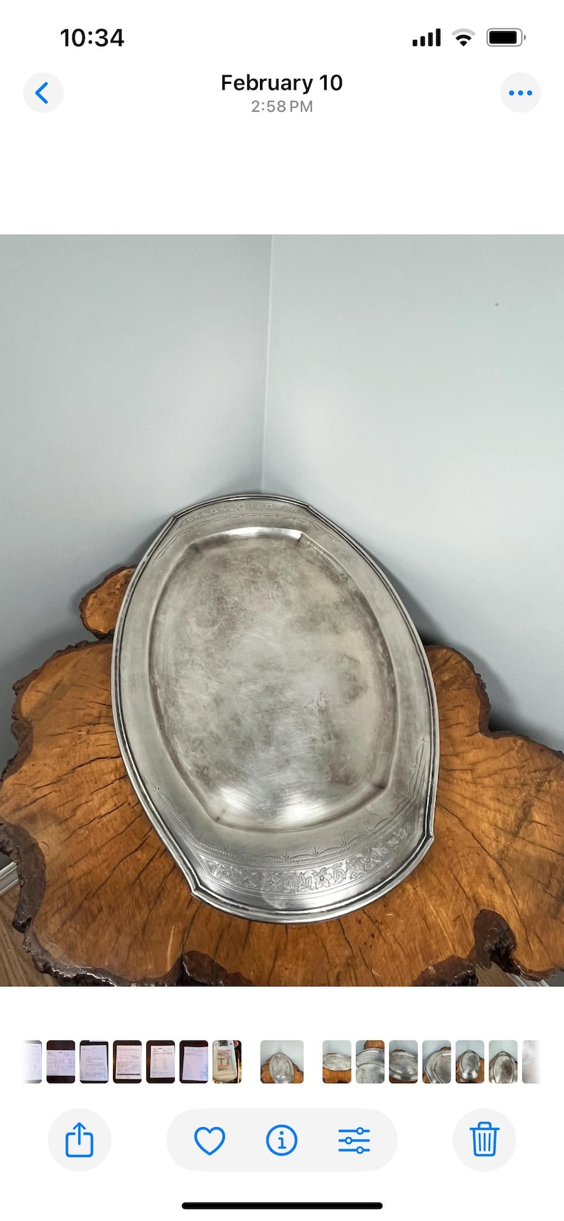 May include: A silver oval serving tray with an ornate design around the edge. The tray is sitting on a wooden surface.