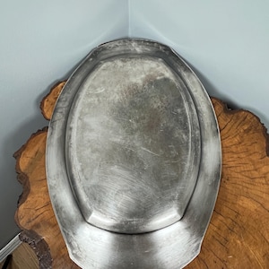 May include: A silver oval serving tray with a raised rim. The tray has a slightly worn, aged look.