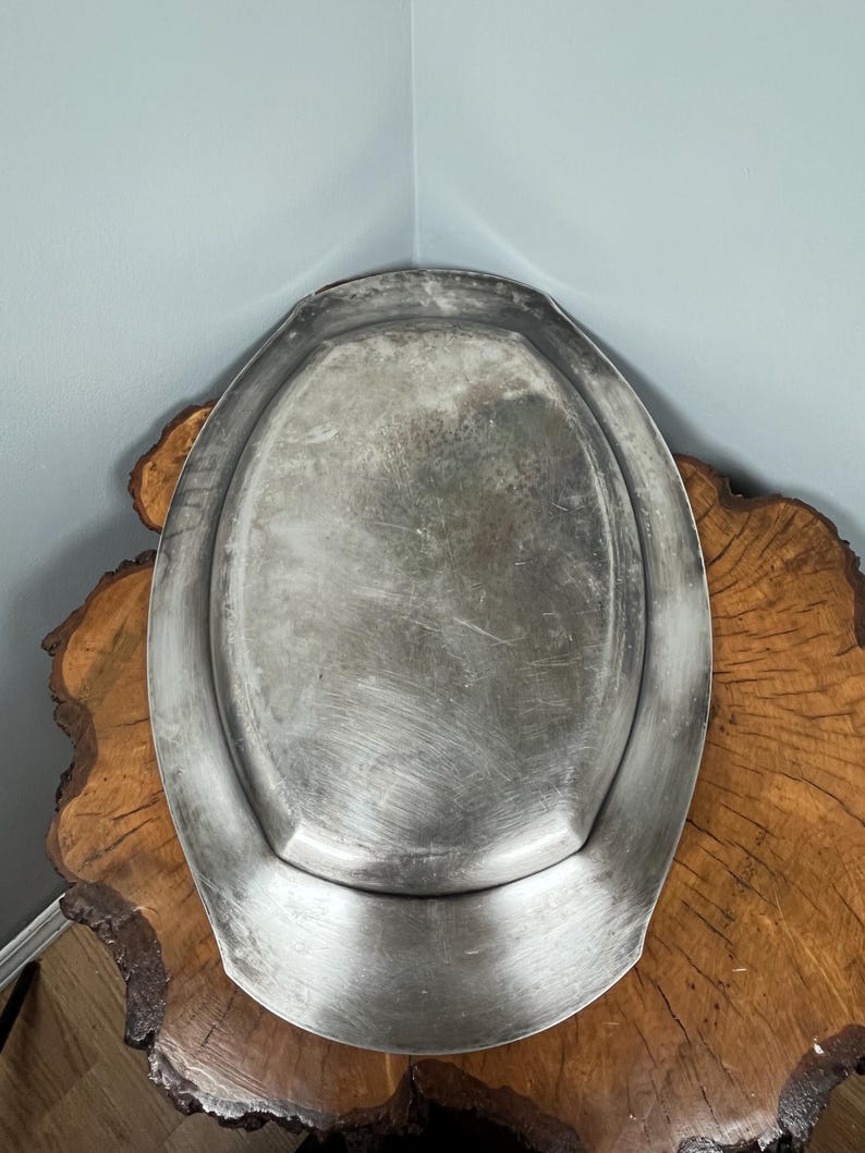 May include: A silver oval serving tray with a raised rim. The tray has a slightly worn, aged look.