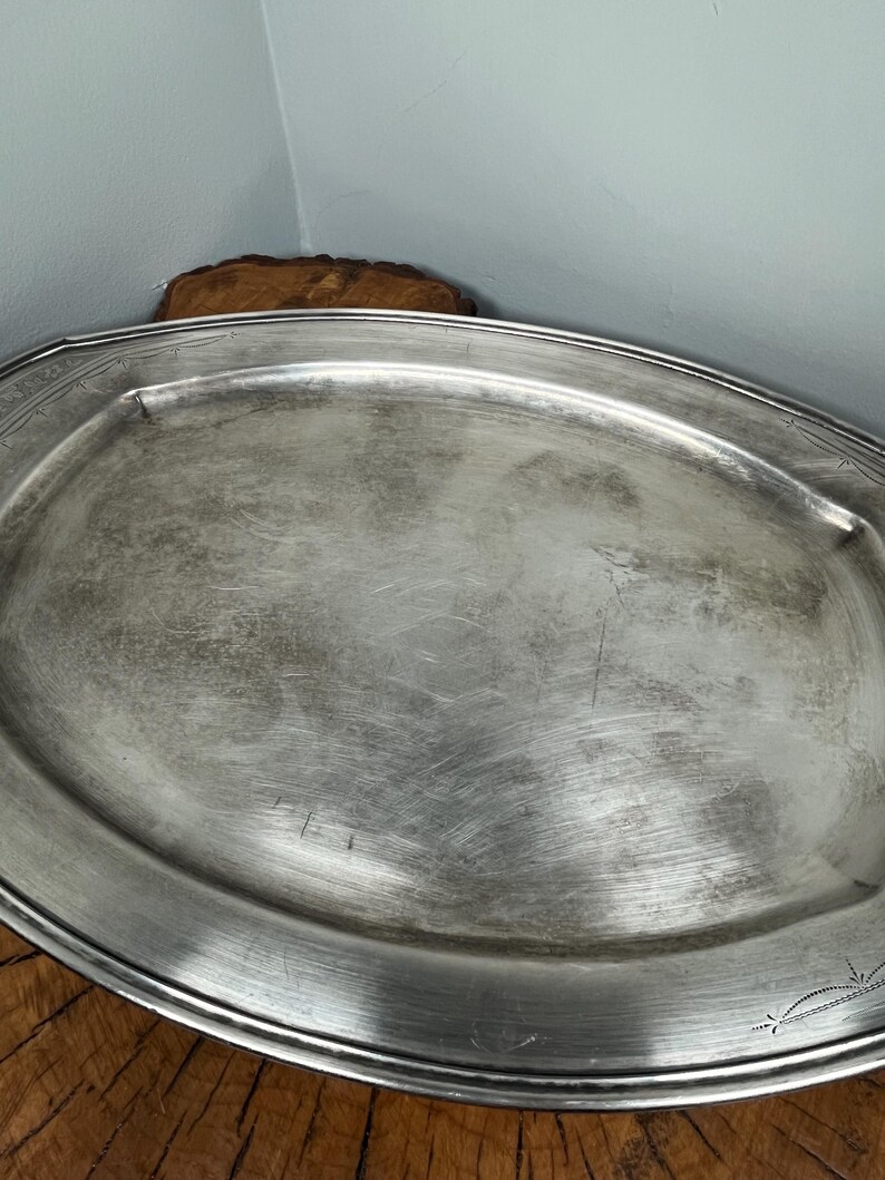 May include: A silver oval serving tray with a decorative border. The tray has a slightly worn, aged look.