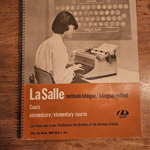 May include: A vintage book cover with a woman using a typewriter. The cover is orange and white, with the text "LaSalle méthode bilingue/bilingual method" and "Cours élémentaire/elementary course". The image also includes the text "Les Frères des Ecoles Chrétiennes/the Brothers of the Christian Schools".