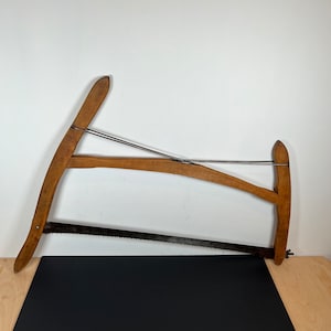 May include: A wooden-handled saw with a long, thin blade. The saw is made of wood and metal and has a traditional design.