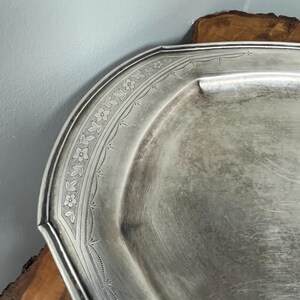 May include: A silver serving tray with a decorative floral pattern around the edge.