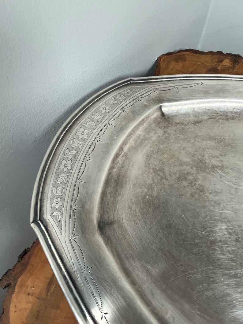 May include: A silver serving tray with a decorative floral pattern around the edge.