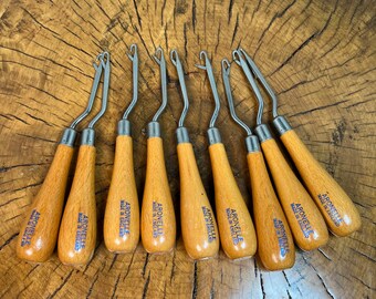 May include: Nine wooden crochet hooks with metal hooks. Each hook has the text "ARONELLE MADE IN ENGLAND" printed on the handle.