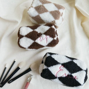 May include: Three brown and white, black and white, and beige and white fuzzy makeup bags with diamond patterns. Each bag has a name embroidered on it: "Eliza", "Erica", and "Sophia".