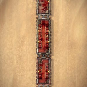 May include: A top-down digital map of a train traveling through a desert. The train consists of four connected cars with red interior flooring, rows of red seats, and scattered dark red stains. The engine car features mechanical details.