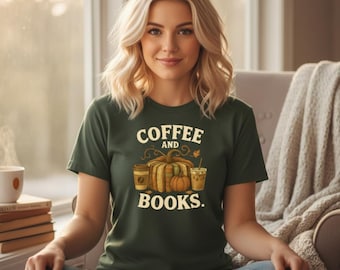May include: A dark green t-shirt with the words "COFFEE AND BOOKS" printed in white. The graphic includes a pumpkin, coffee cups, and fall leaves. The person is sitting in a chair.