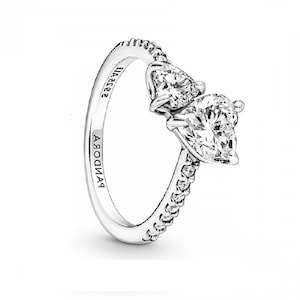 May include: A silver ring featuring two pear-shaped clear stones and a row of smaller clear stones around the band. The ring is engraved with "PANDORA" and "S925 ALE".