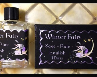 May include: A small glass bottle with a black cap and a label that reads "Winter Fairy Sage - Pine English Moss". The bottle is next to a black box with a similar label.