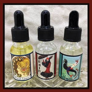 Può includere: Tre bottiglie di vetro con contagocce e etichette. Le etichette presentano illustrazioni di una donna con un vestito rosso, un cavalluccio marino e una donna con un fiore tra i capelli. Le etichette riportano anche le parole "Rain", "Ocean" e "Fresh Linen".