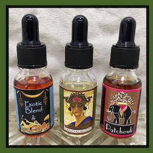 May include: Three small glass bottles with black dropper tops and labels. The bottles contain different colored liquids. The labels have different designs and text. The labels read "Exotic Blend", "Sandalwood", and "Patchouli".