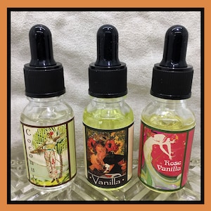 Puede incluir: Tres botellas de vidrio con tapas de gotero negras y etiquetas. Las etiquetas presentan ilustraciones vintage de mujeres y las palabras "Coconut", "Vanilla" y "Rose Vanilla".