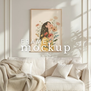 Può includere: Un'illustrazione incorniciata di una donna con fiori nei capelli, in piedi davanti a un muro bianco con un divano in primo piano. Il testo "FRAME mockup" è scritto sotto la cornice.