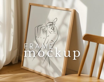 May include: A wooden frame with a white mat and a black and white line drawing of two hands intertwined. The frame is leaning against a wooden chair in a room with white walls and a white curtain.