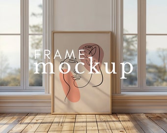 May include: A framed illustration of a line drawing of a face with a rose and leaves. The background is a light beige color with a pink and peach abstract shape. The frame is a light wood color. The text "FRAME mockup" is superimposed on the image.