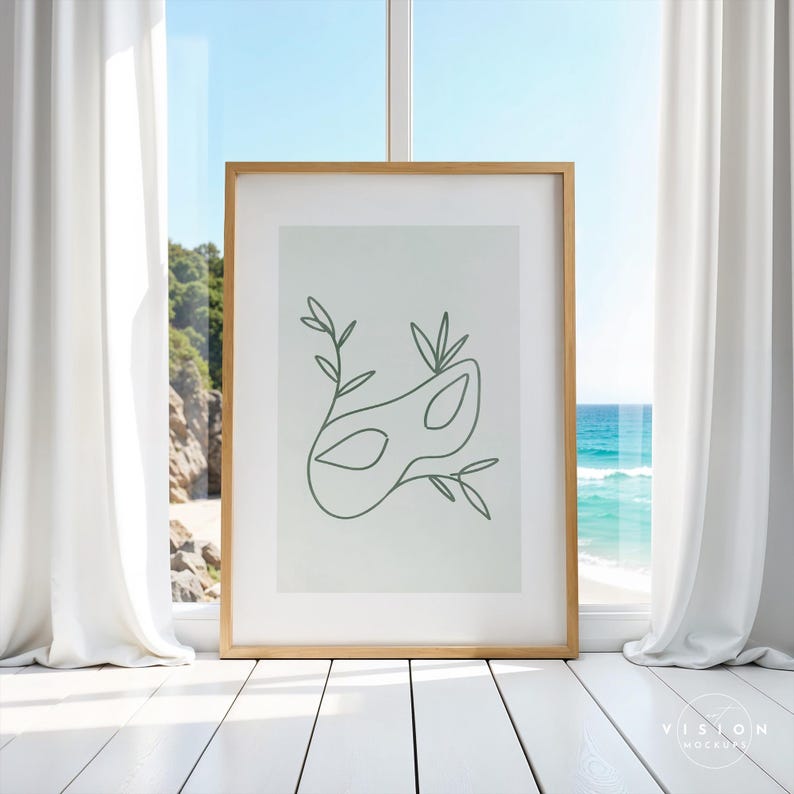 May include: A framed print with a minimalist line drawing of a masquerade mask with leaves on a light green background.