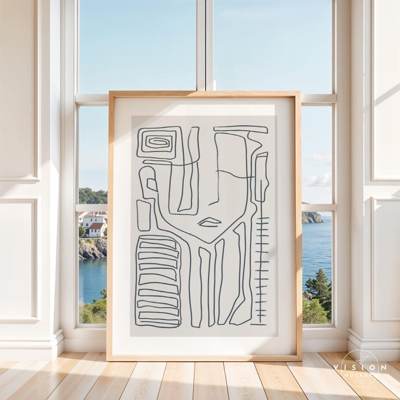 May include: A black and white line art print of an abstract face with geometric shapes. The print is framed in a light wood frame and is hanging on a wall.