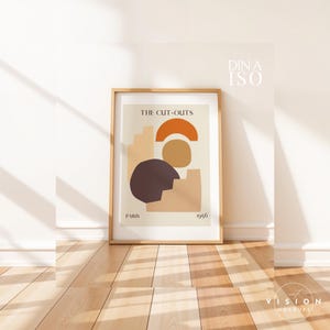 May include: A framed print with a minimalist abstract design in shades of brown, orange, and beige. The print is titled "The Cut-Outs" and includes the text "Paris 1956".