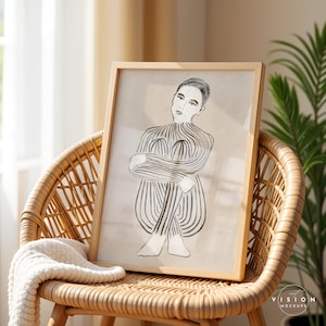 Pode incluir: Um desenho a preto e branco de uma pessoa sentada com os bra&ccedil;os cruzados. O desenho est&aacute; sobre um fundo bege e est&aacute; emoldurado numa moldura de madeira clara.
