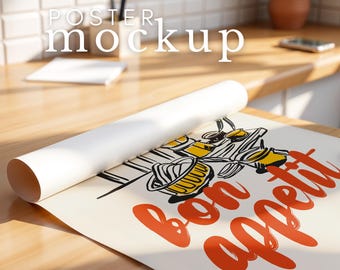 May include: A white poster mockup rolled up on a wooden surface. The poster features a black and white illustration of a kitchen scene with the text "bon appetit" in red.