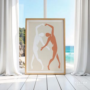 May include: A framed print of a minimalist abstract art piece featuring two figures in a dance pose. The figures are outlined in white and peach against a light beige background.